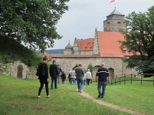 Gruppe wander über eine Wiese zur Burg