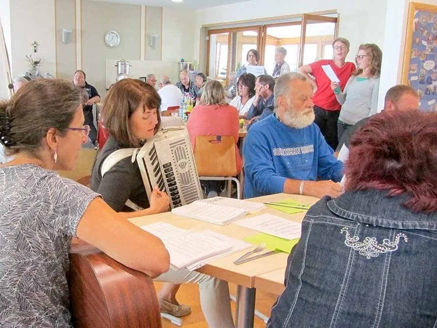 Präsentation im Aufenthaltsraum: es scheinen alle da zu sein. Ein Mann mit grauem Bart stellt seine Arbeit vor.