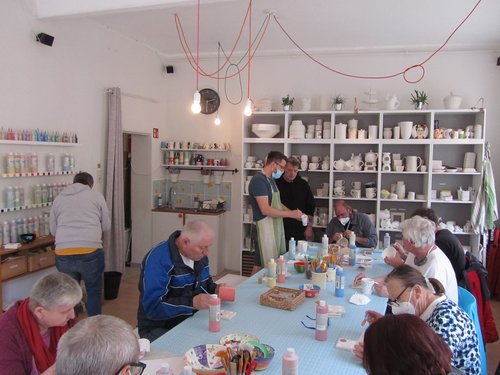 Gruppe beim Bemalen von Tassen und anderer Keramik